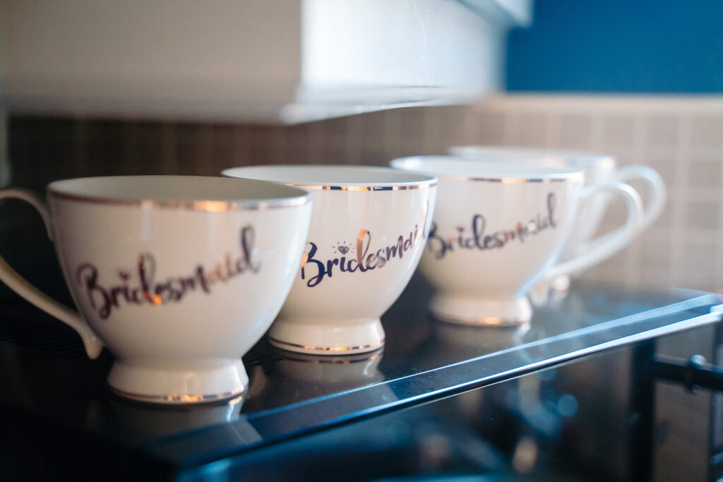 White teacups with Bridesmaid text and gold trim displayed