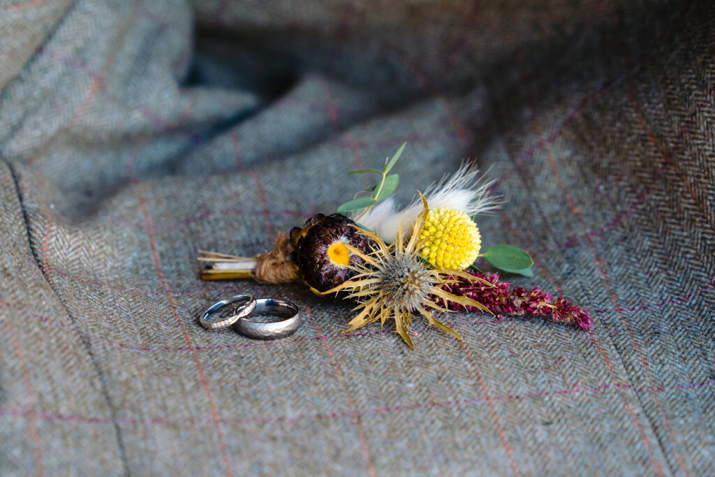 Wedding rings and dried flower bouquet on tweed fabric