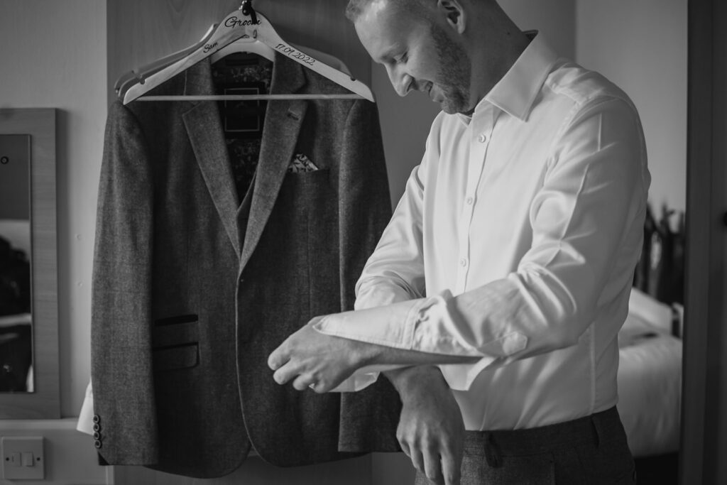 Groom examining grey suit jacket on personalised hanger