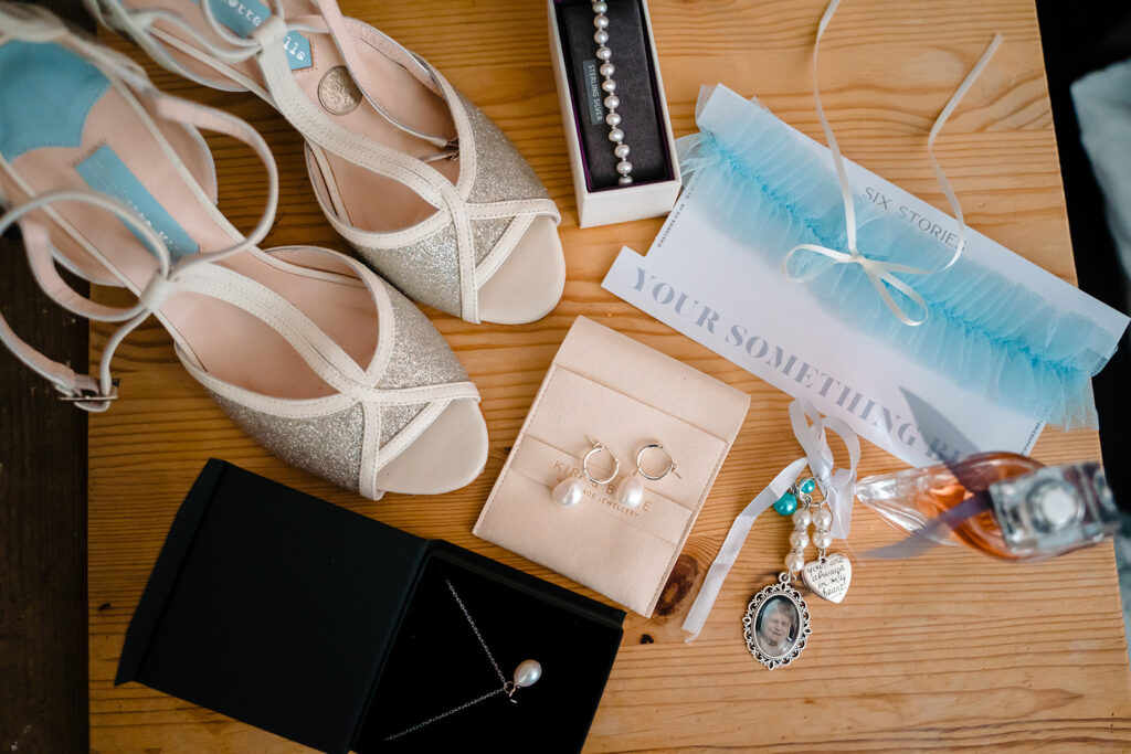 Bridal accessories including heels, jewellery and gifts on wooden surface
