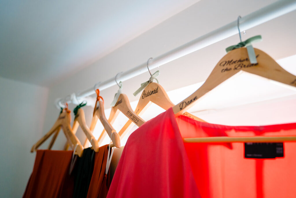Wooden wedding hangers with bridesmaid dresses hanging on rail