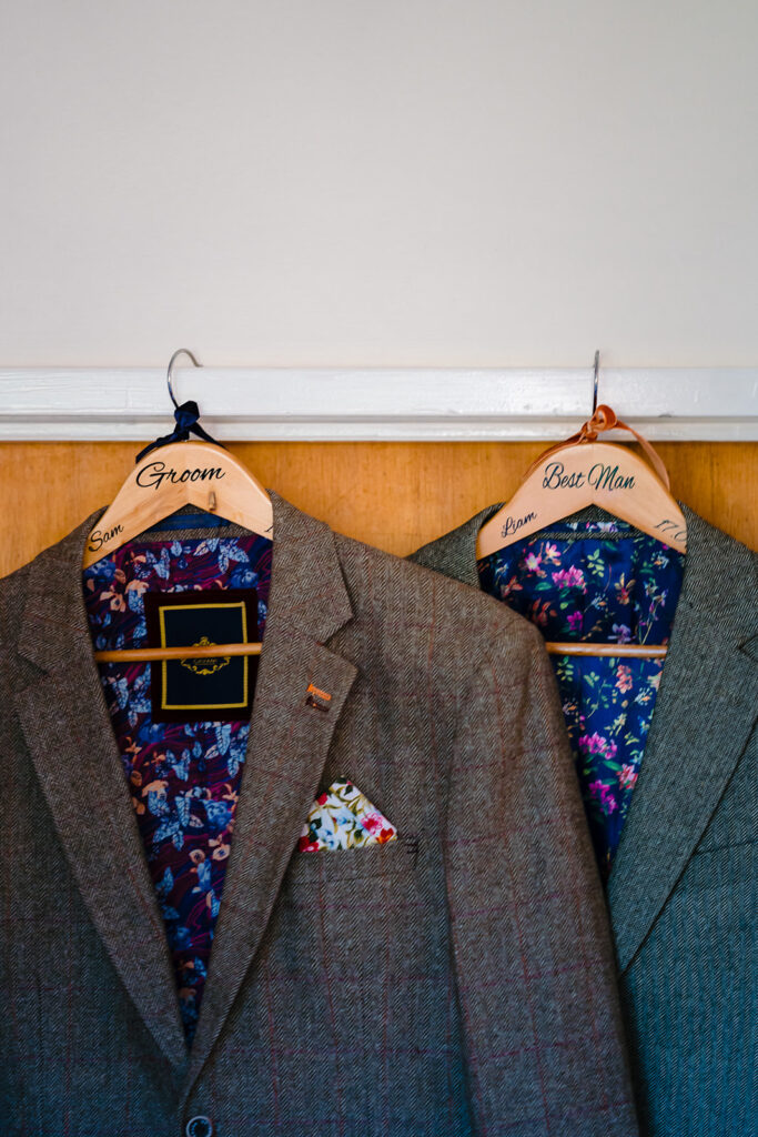 Groom and Best Man wedding suits on personalised wooden hangers