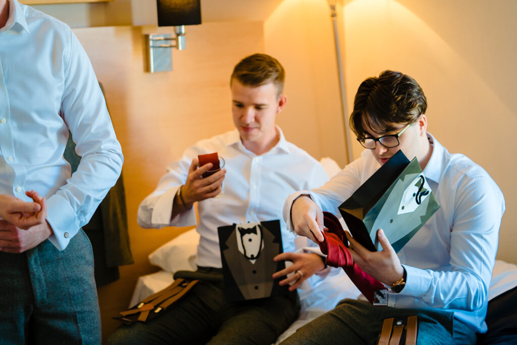 Three men in formal wear examining red bow ties together