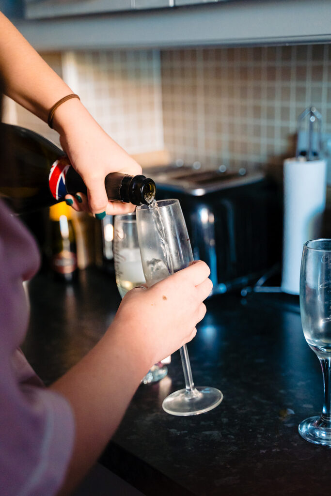 Person pouring white wine into glass in kitchen
