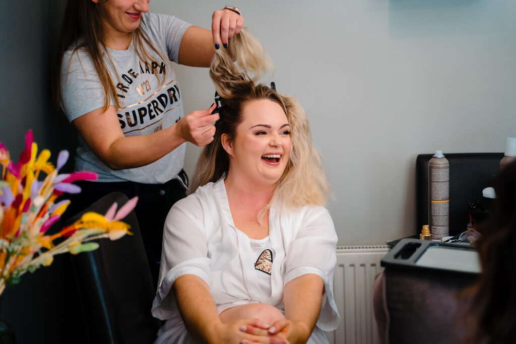 Hairstylist curling client's blonde hair in salon
