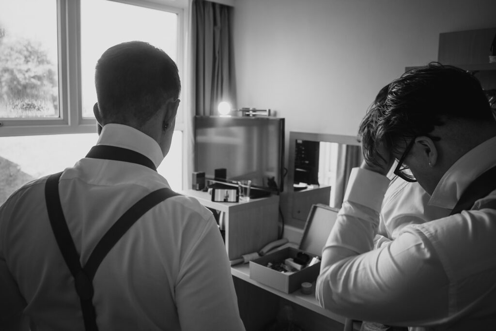 Two men in white shirts preparing in modern hotel room
