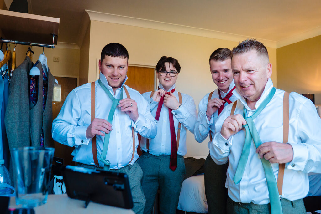 Five men in formal attire displaying neckties indoors