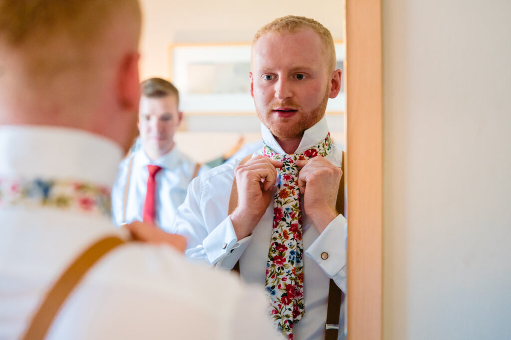 Groom adjusting floral tie before wedding ceremony