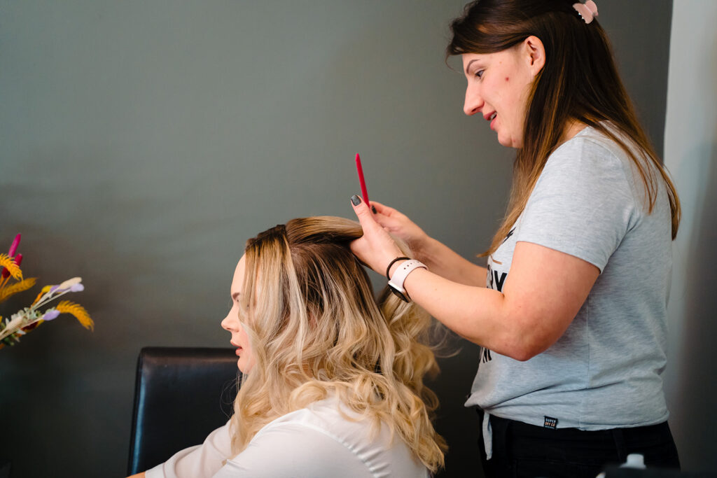 Hairstylist curling blonde hair with red curling iron