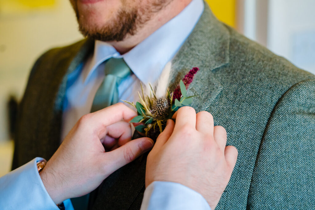 Groom wearing buttonhole flower on tweed jacket