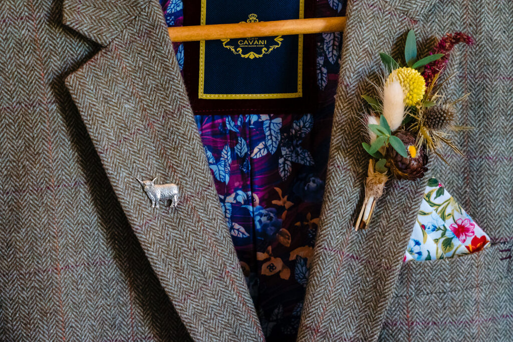 Tweed jacket with goat brooch and floral accessories displayed
