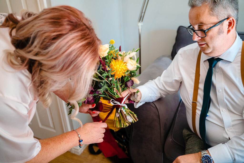 Man giving woman colorful flower bouquet indoors