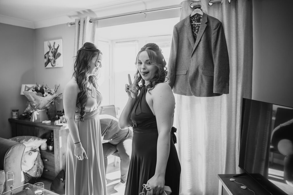 Two women in elegant dresses admiring grey blazer indoors