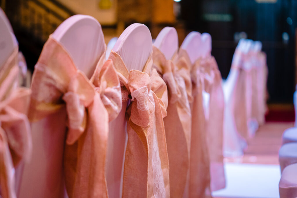 Pink chair covers with bows at event venue