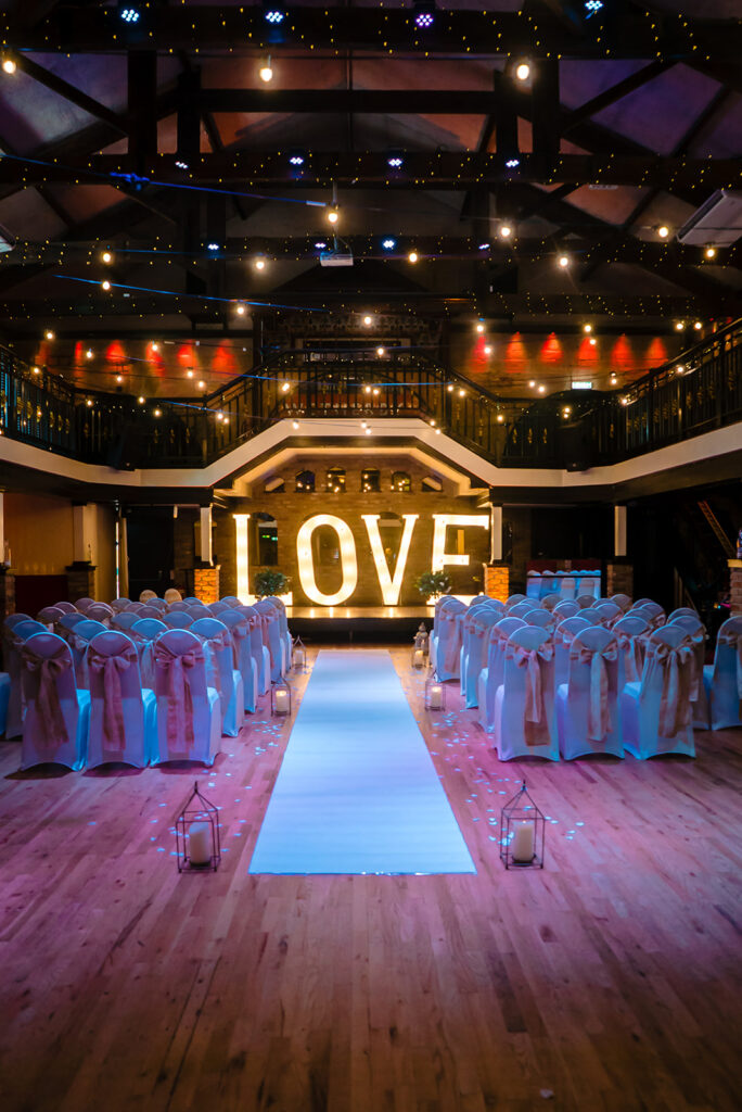 Elegant wedding ceremony venue with LOVE sign and pink chairs