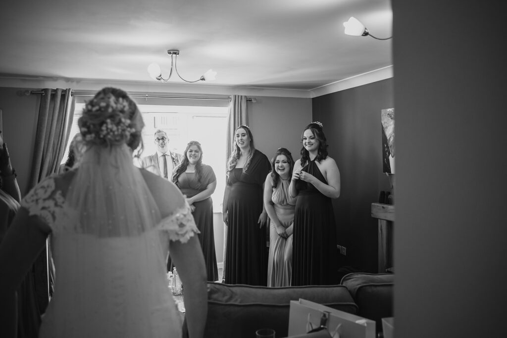 Bride in wedding dress reveals herself to smiling wedding guests