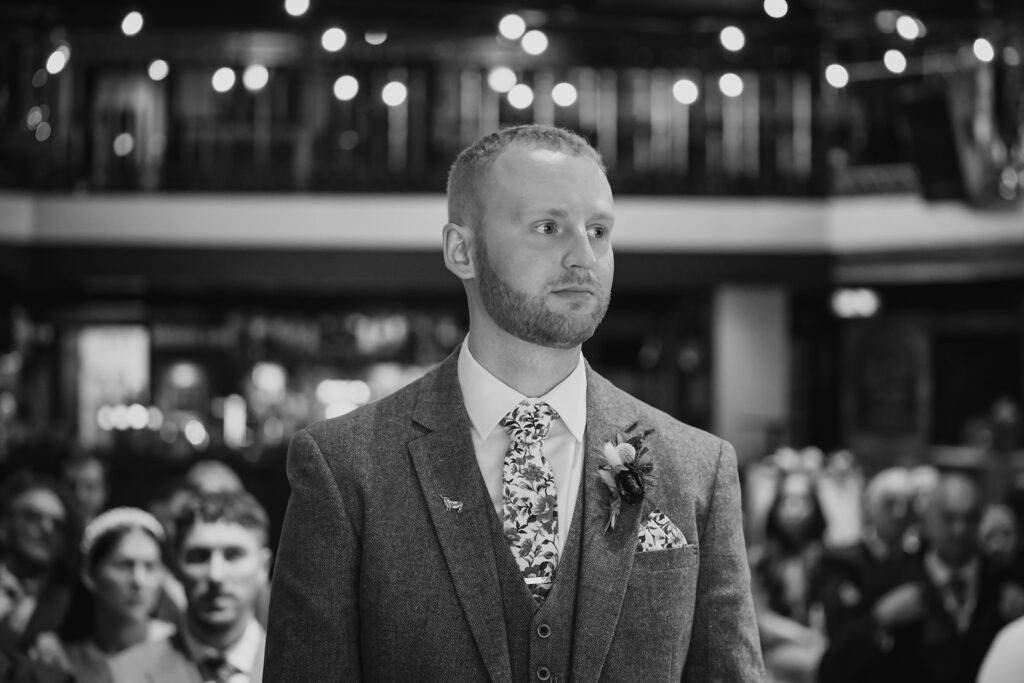 Groom in grey suit at wedding ceremony, black and white portrait