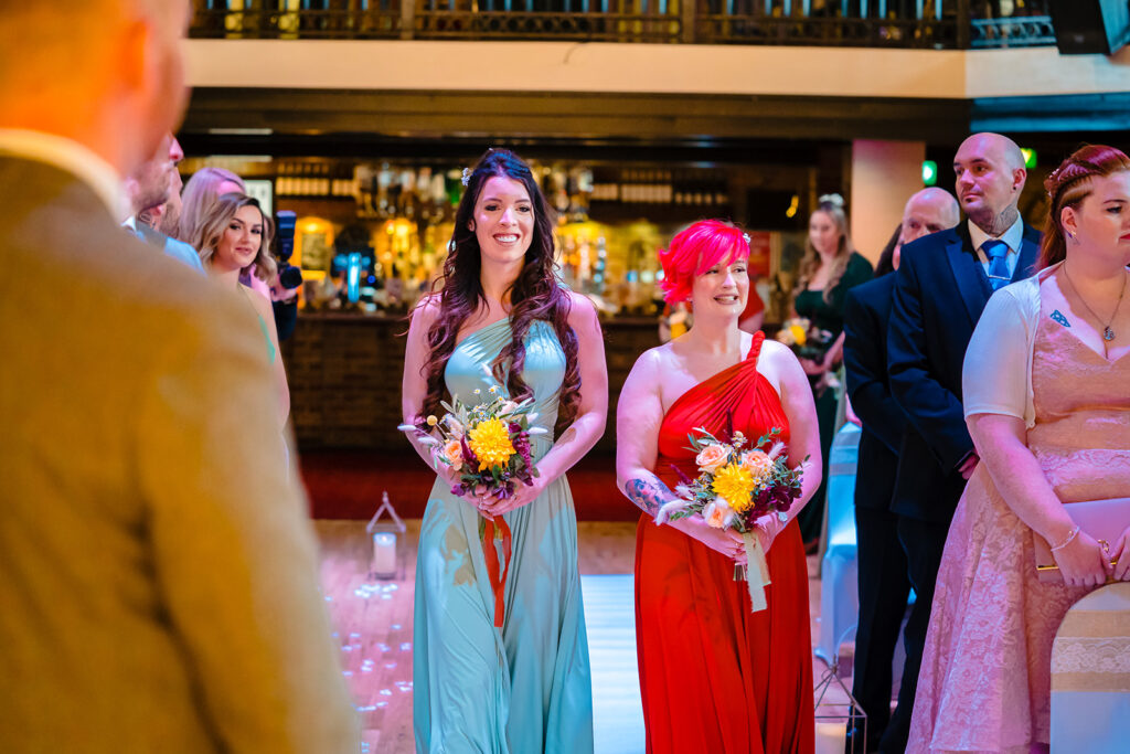 Two women holding flowers at formal event in elegant venue