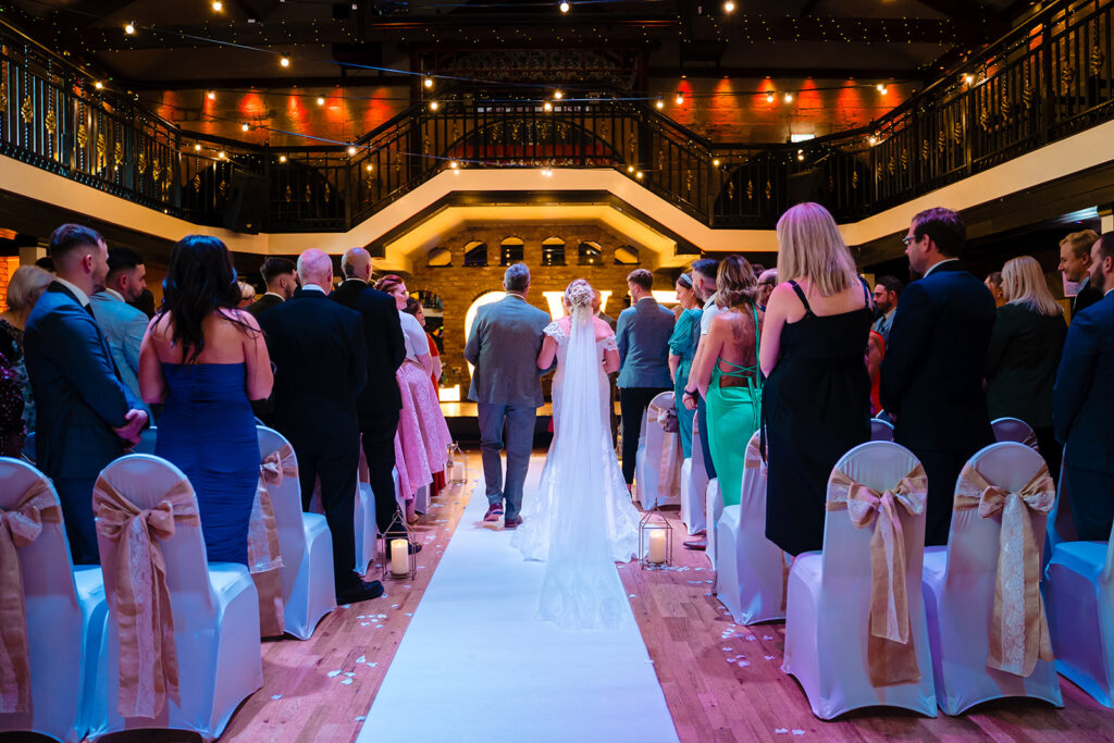 Elegant wedding ceremony in grand ballroom with white aisle runner