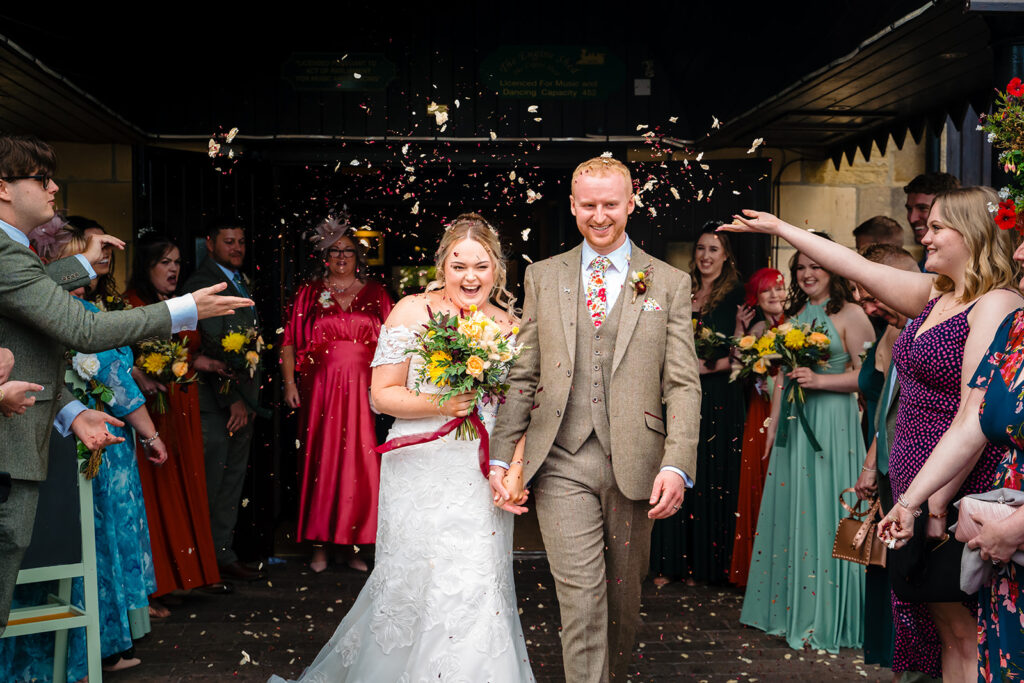 Bride and groom walking through confetti shower at wedding reception