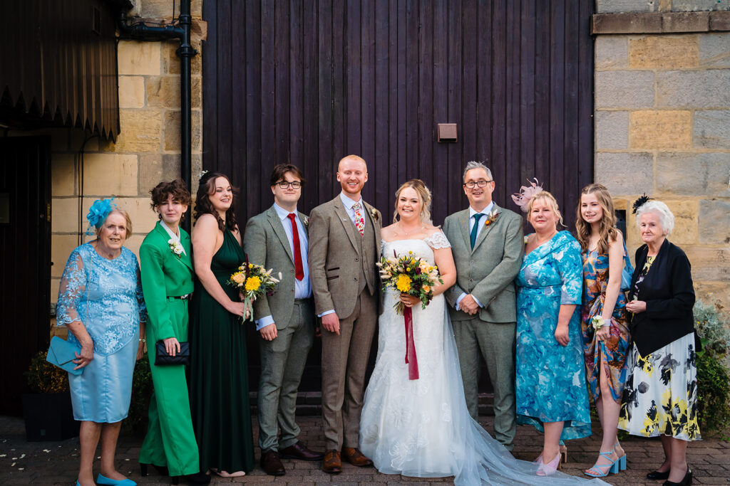 Wedding party group photograph with bride, groom and guests