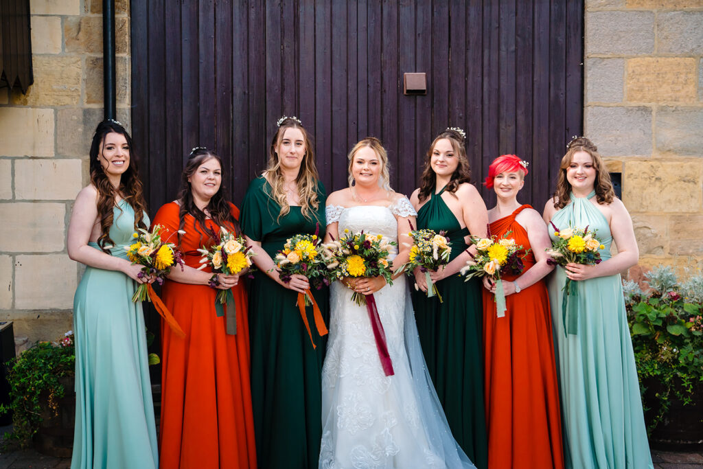 Bride and bridesmaids in colourful dresses holding yellow flowers