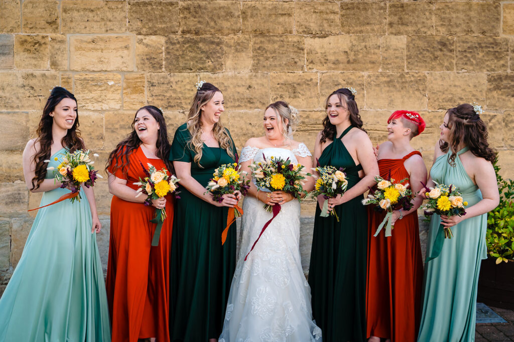 Bride and bridesmaids in colourful dresses holding yellow flower bouquets