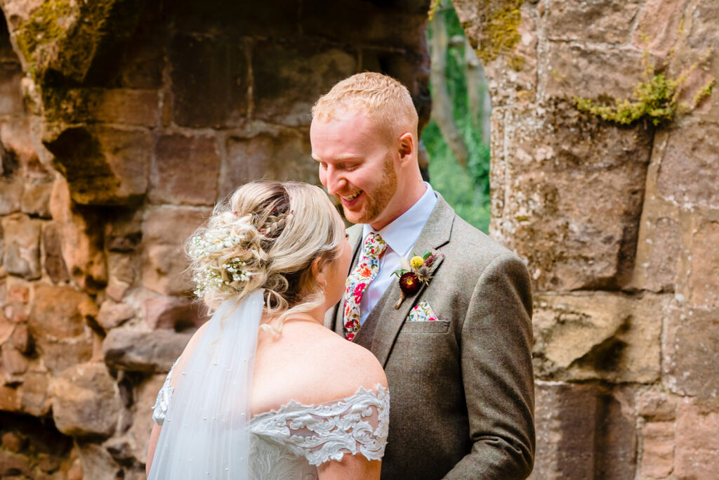 Bride and groom smiling at historic stone ruins location