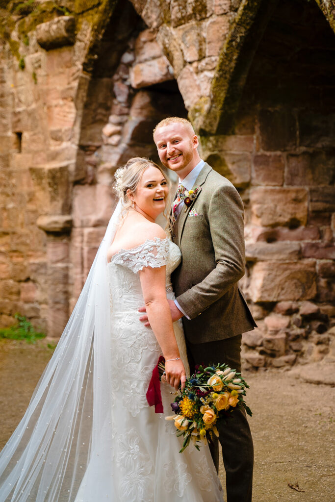 Bride and groom smiling at historic stone ruins