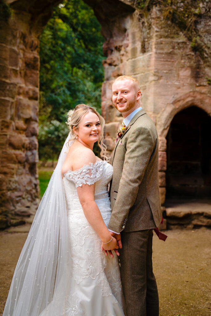 Bride and groom posing at historic stone ruins