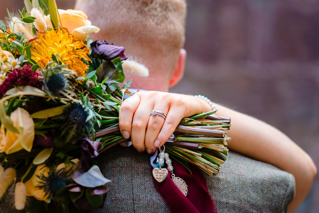 Bride holding colourful wedding bouquet displaying engagement ring