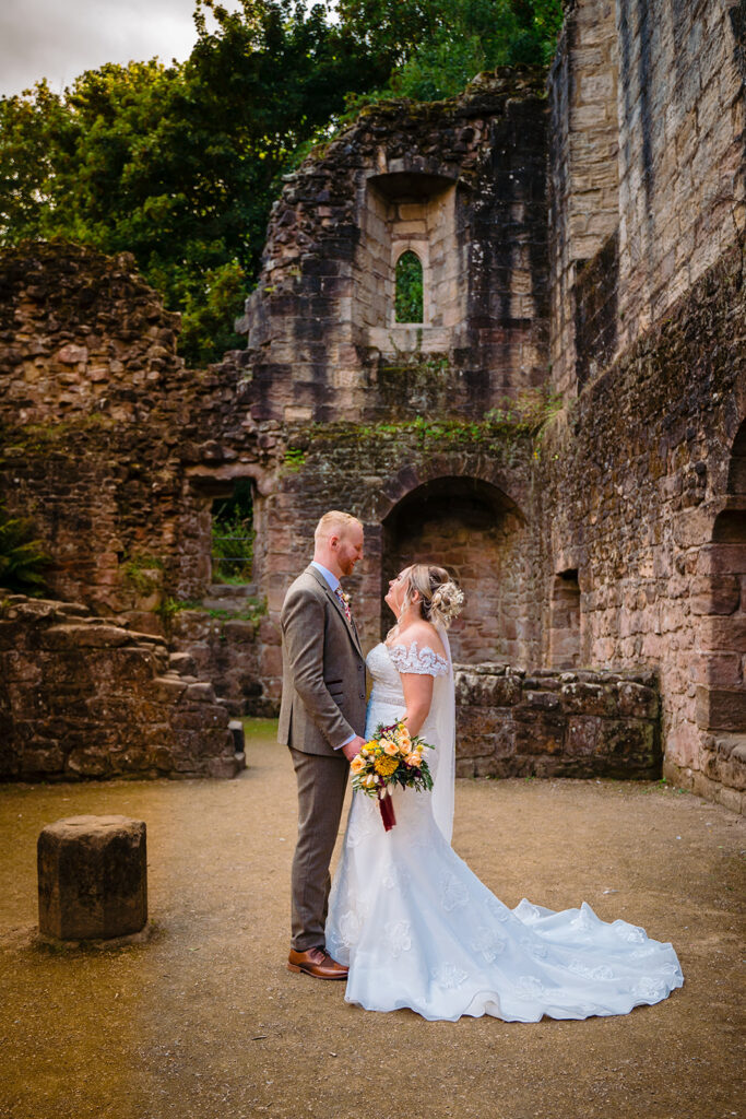 Bride and groom posing at historic stone castle ruins