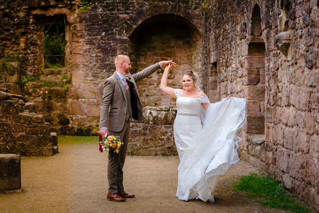 Bride and groom dancing at historic stone castle ruins