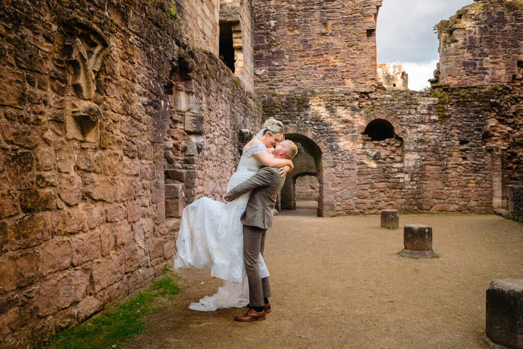 Bride and groom kissing in historic castle ruins