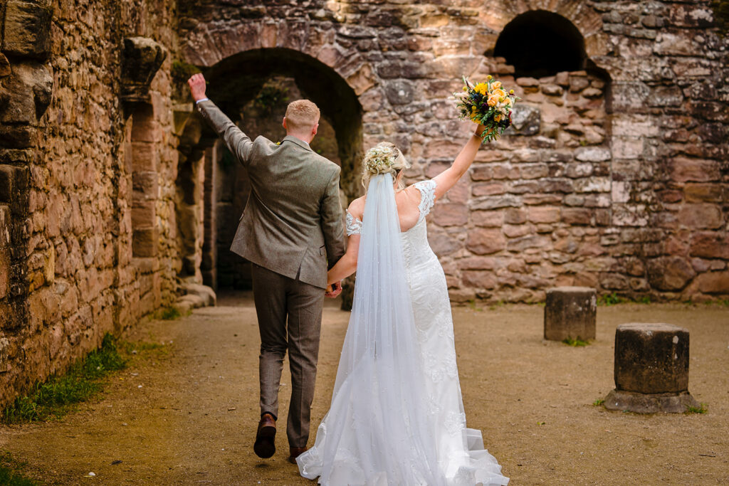 Bride and groom celebrating in historic stone castle ruins
