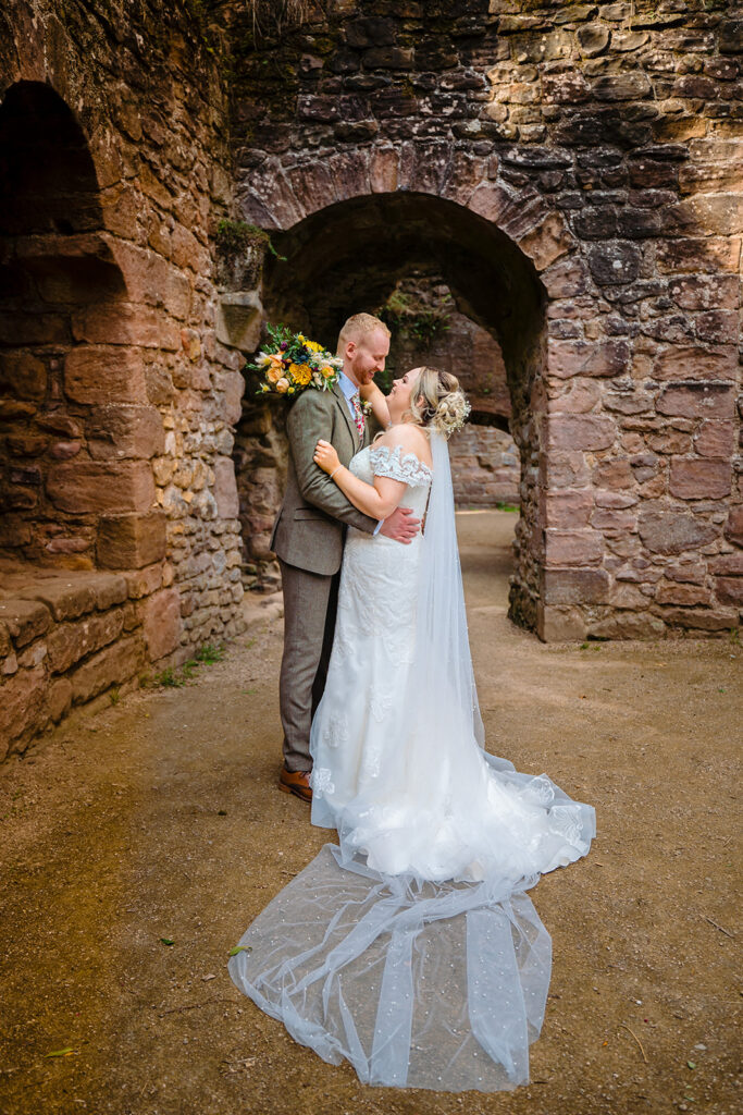 Bride and groom posing at ancient stone archway ruins