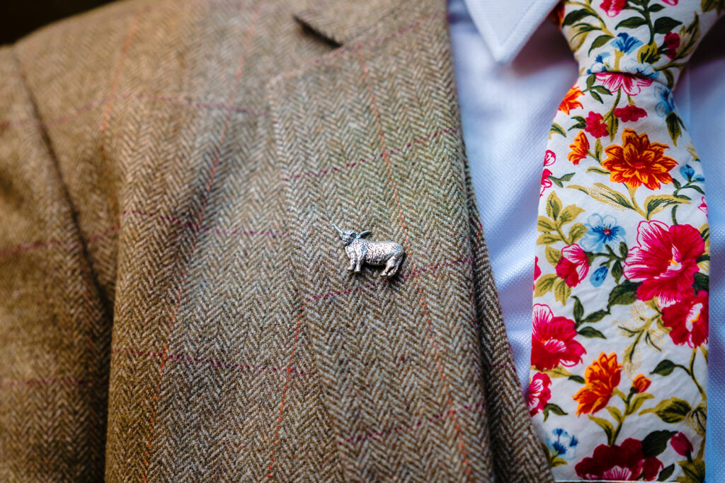 Silver sheep brooch on tweed jacket with floral tie