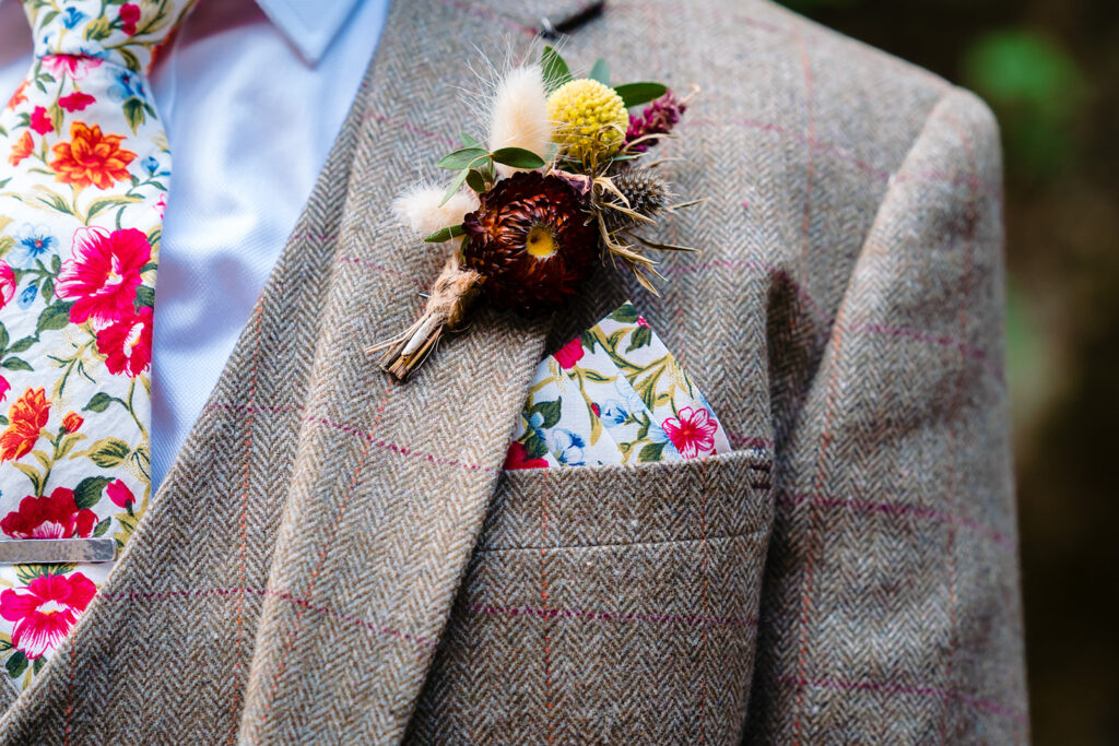 Rustic boutonniere pinned on grey tweed wedding jacket
