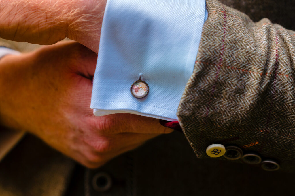 Person wearing blue cufflinks with globe design on shirt sleeve