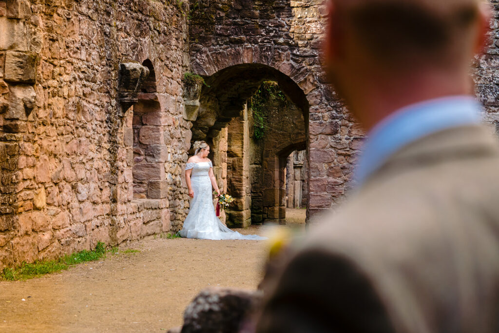 Bride in white dress at ancient stone archway ruins