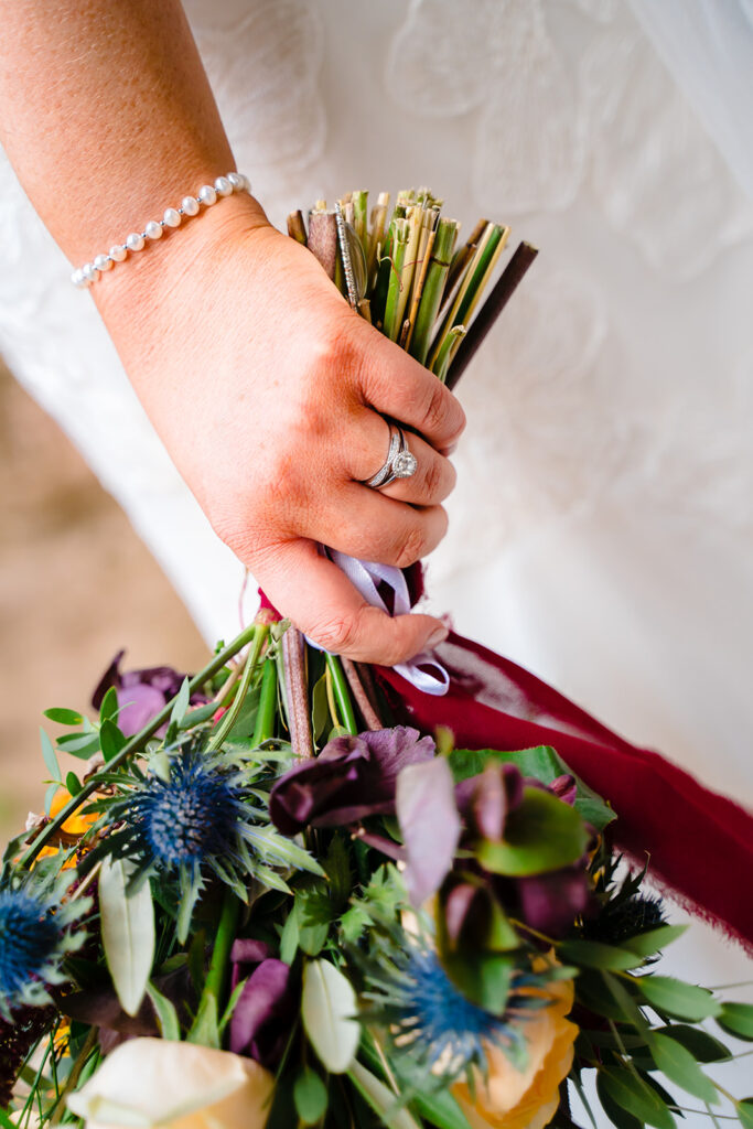 Bride's hand holding wedding bouquet wearing diamond ring