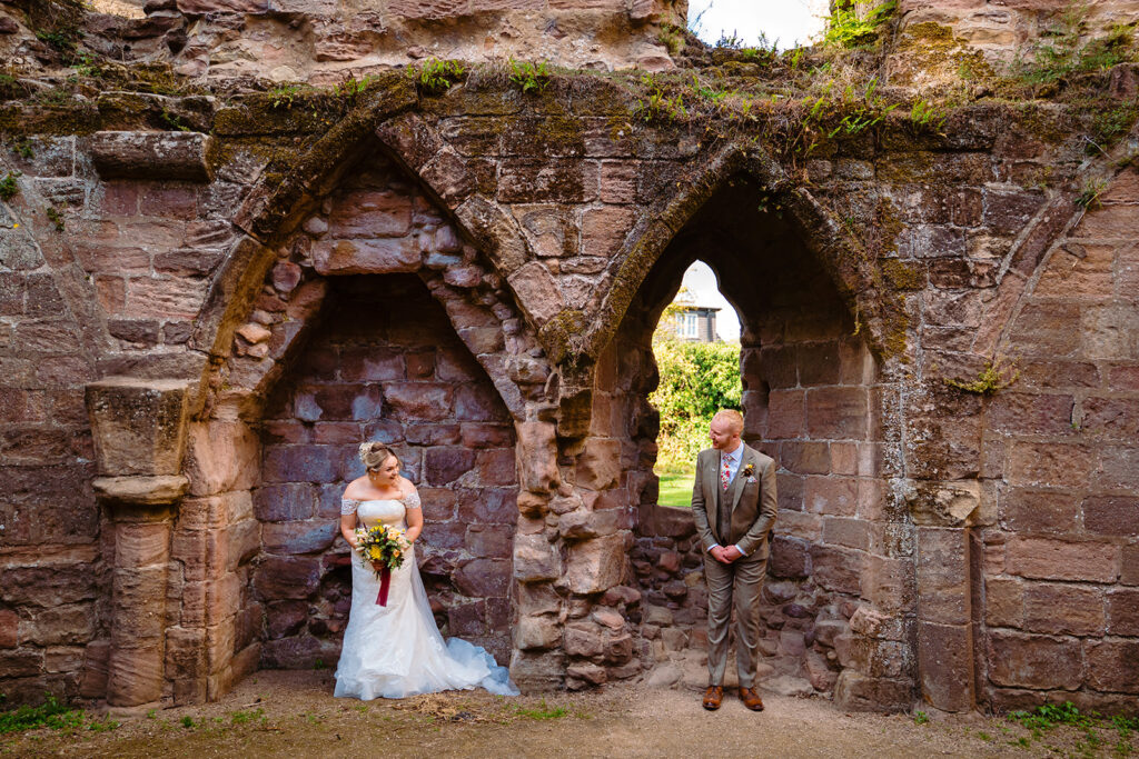 Bride and groom posing at ancient stone archway ruins