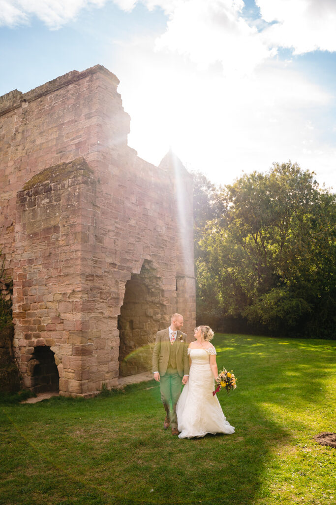 Bride and groom at historic stone castle ruins in sunlight