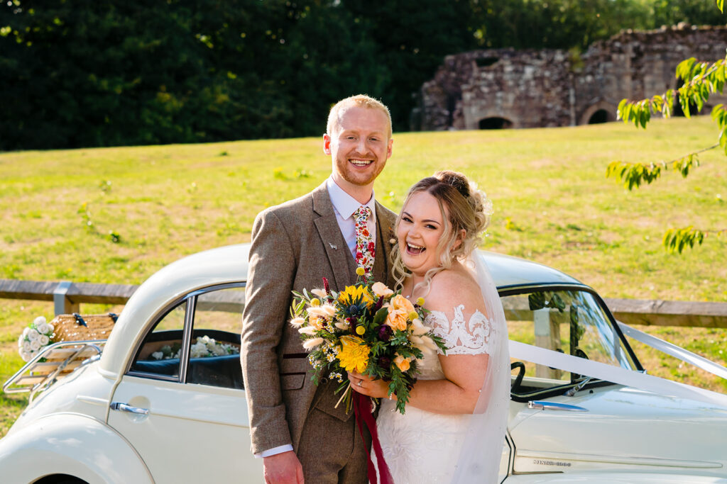 Smiling bride and groom with vintage car and castle