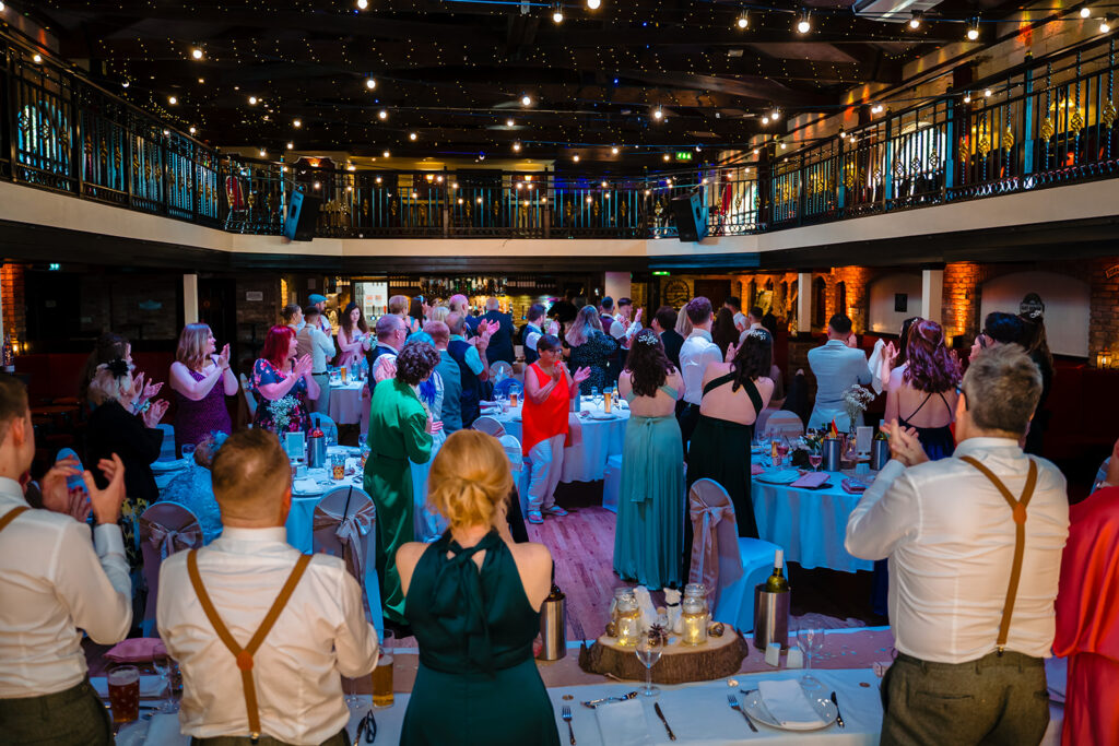 Elegant ballroom event with guests dining at blue-clothed tables