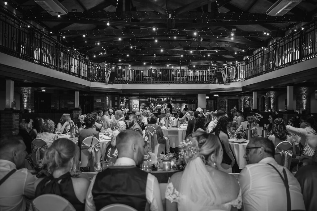 Black and white wedding reception in elegant ballroom with guests dining