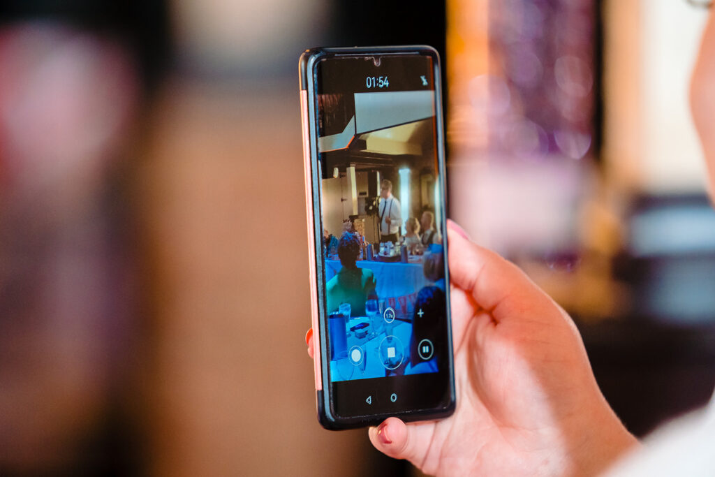 Person holding smartphone recording video at event