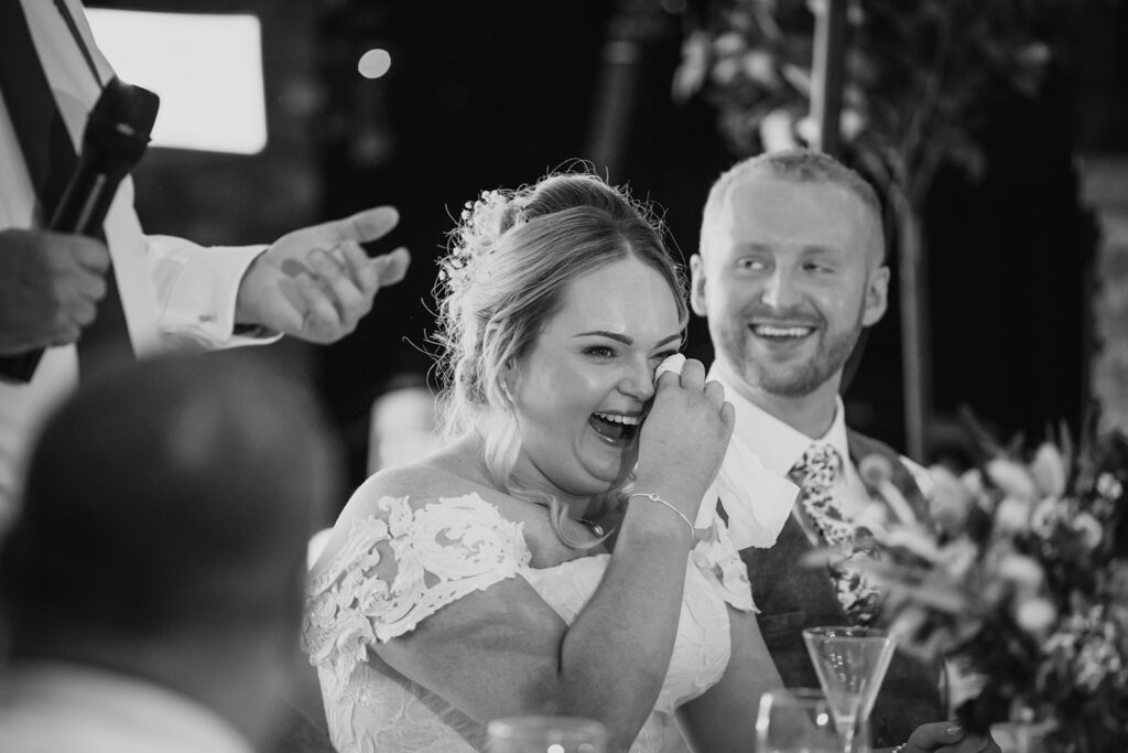 Bride and groom laughing joyfully at wedding reception