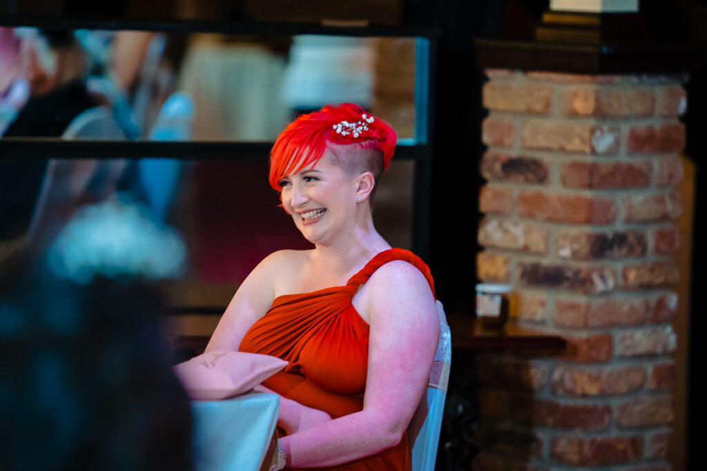 Woman with bright red hair wearing red dress and pearl tiara