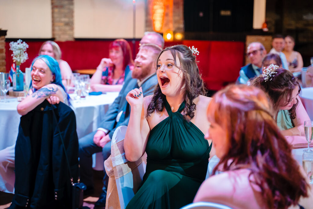 Woman in green dress celebrating at formal wedding reception dinner